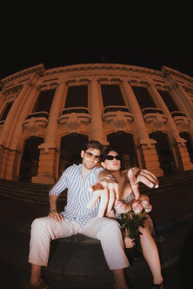 A couple sitting in front of a classical building with columns. 1