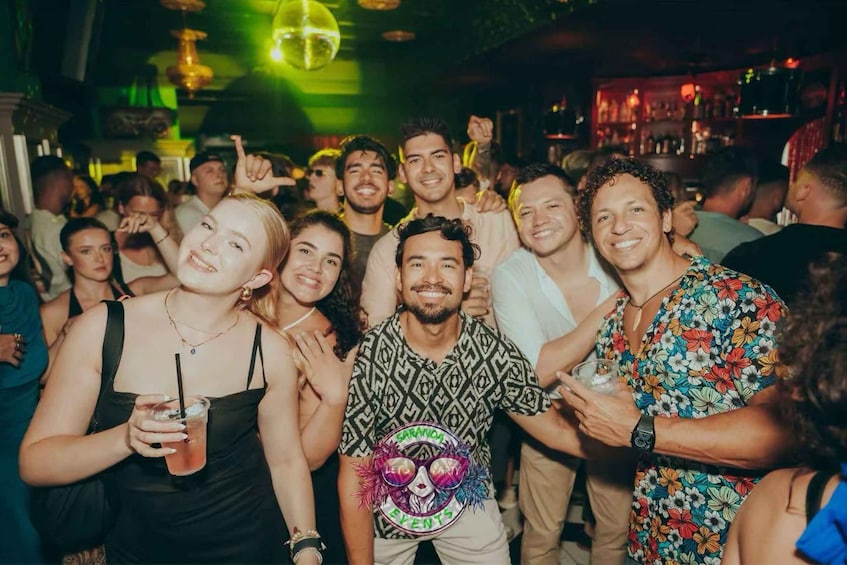 A group of people at a social event, possibly a party or gathering, with a bar in the background. 1