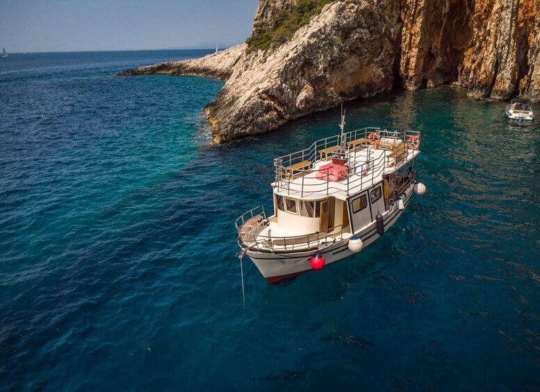 A boat anchored near a rocky coastline with clear blue water. 1
