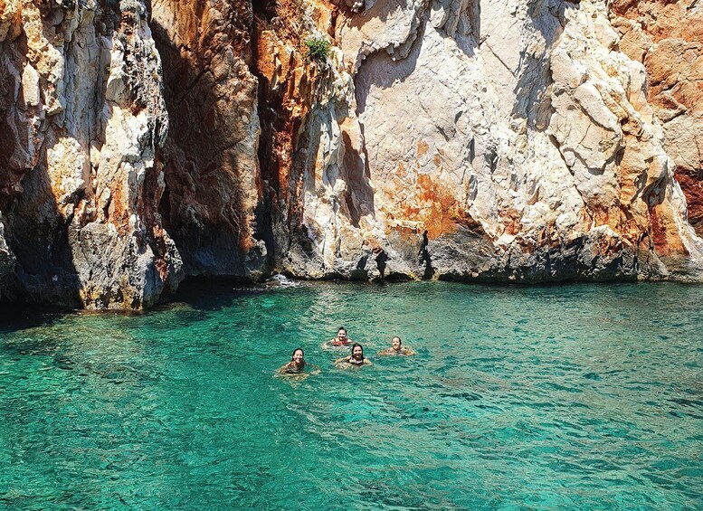 A group of people swimming in clear turquoise water surrounded by rocky cliffs. 5