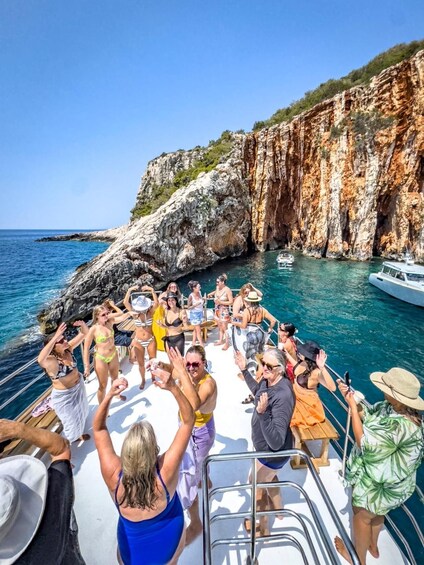 A group of people on a boat near rocky cliffs and clear blue water. 5