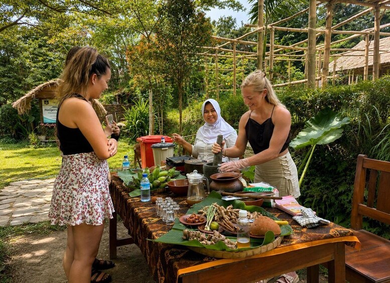 A group of people preparing food outdoors with a table set with various ingredients and cooking utensils. 1