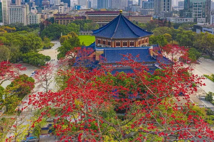 A traditional pavilion with a blue roof surrounded by red foliage, set against a cityscape. 4