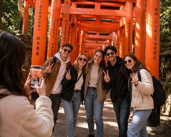 A group of people taking a photo in front of a red torii gate. 3