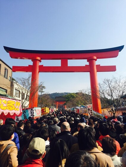 A crowd at a traditional Japanese torii gate with a clear sky. 4