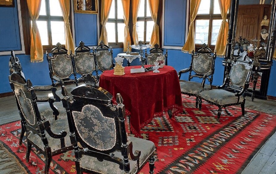 A room with ornate furniture, a red tablecloth, and patterned rugs. 3