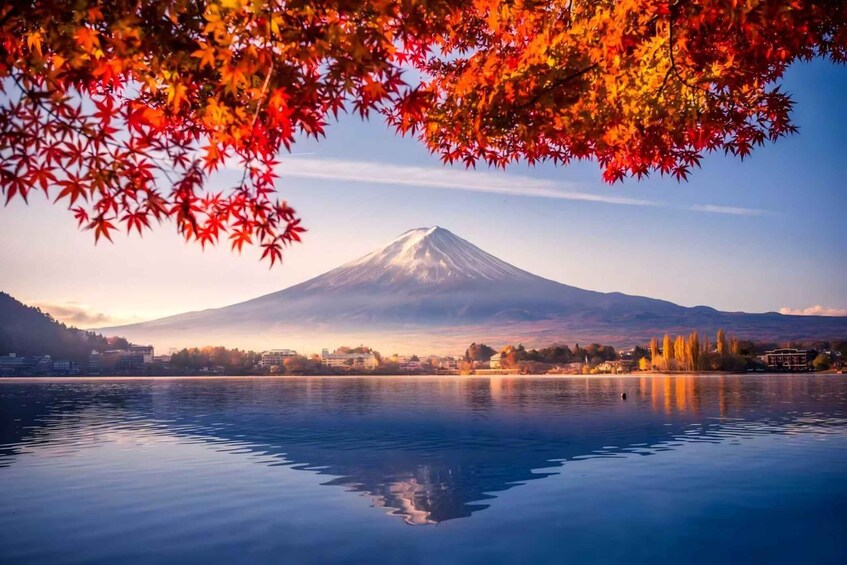A calm lake with a reflection of a mountain and autumn leaves in the foreground. 1