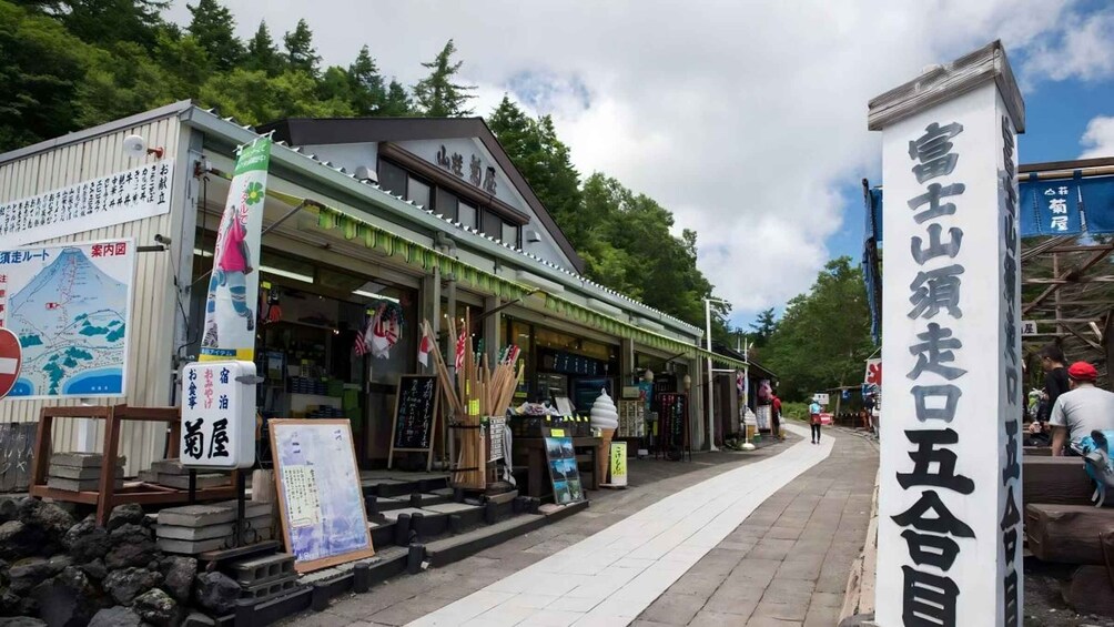 A traditional Japanese building with a signboard, a map, and various items displayed outside. 2