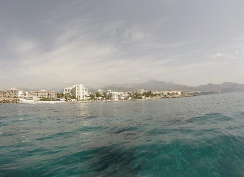 A coastal cityscape with a clear view of the sea and mountains in the distance. 3