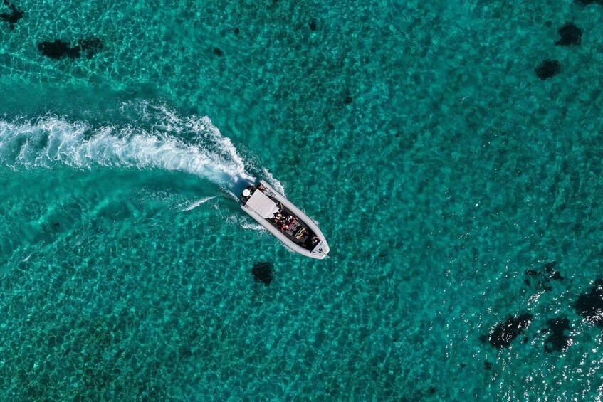 An aerial view of a boat on clear turquoise water with visible coral formations. 5