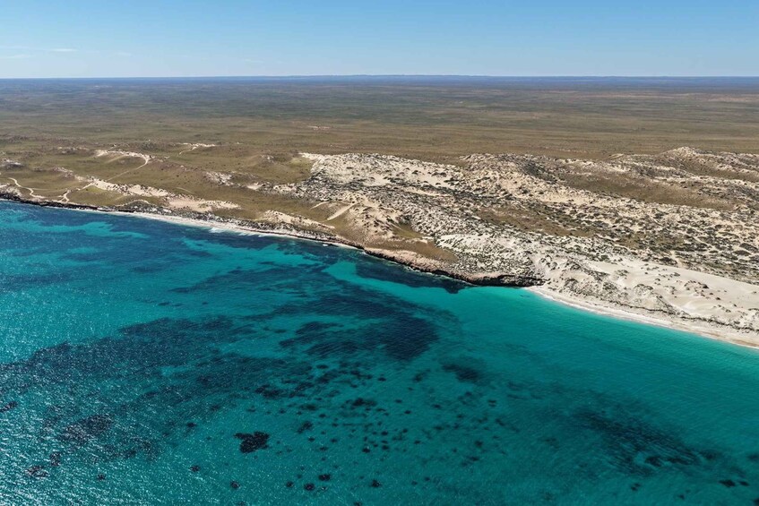 A coastal landscape with a sandy beach and clear turquoise waters. 3