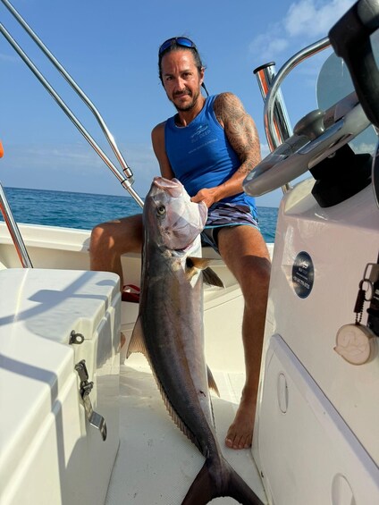 A person on a boat holding a large fish. 1