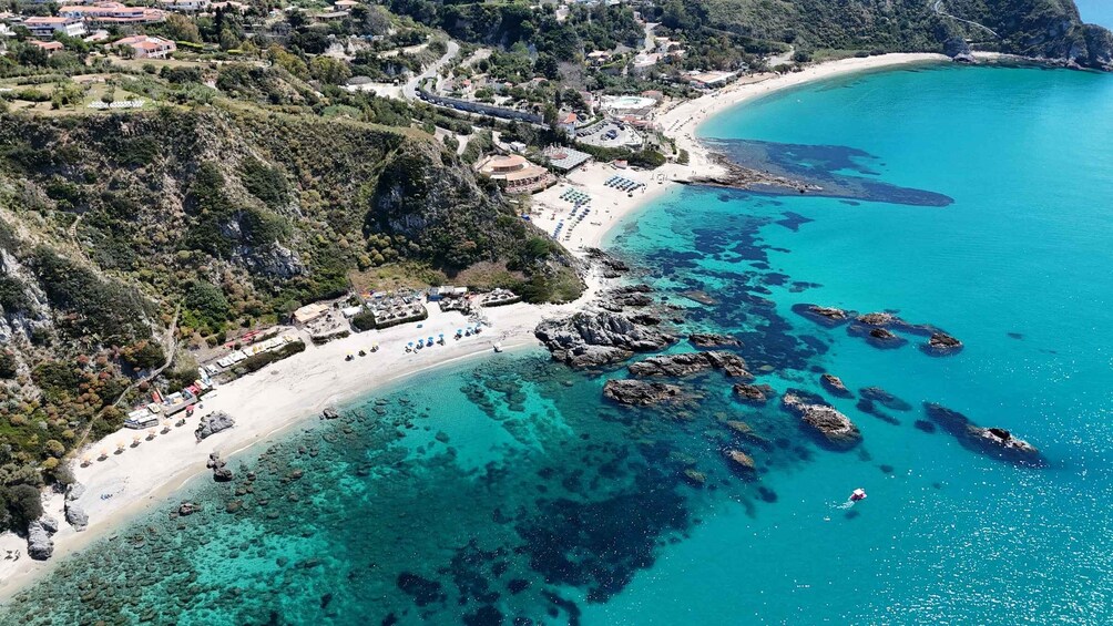 A coastal town with a beach, rocky shoreline, and clear turquoise waters. 4