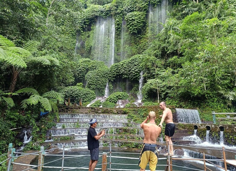 A waterfall in a lush forest with people taking photos. 3