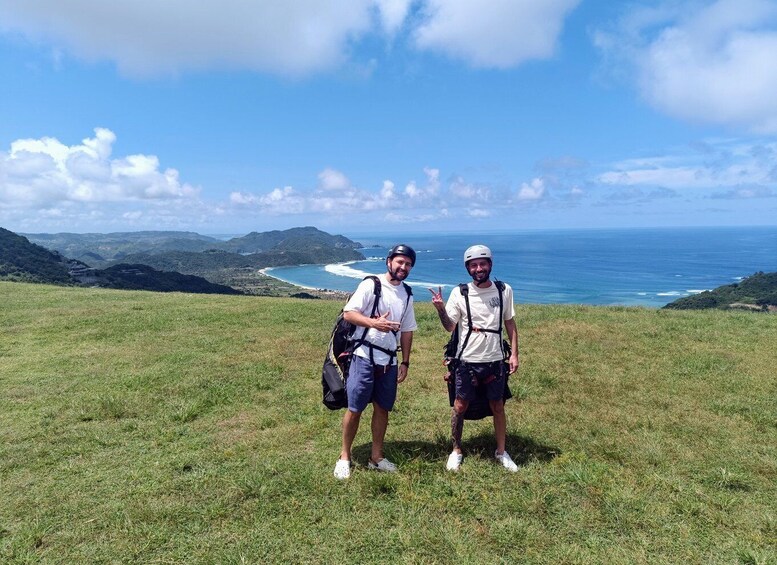 Two people standing on a grassy hill with a coastal view. 4