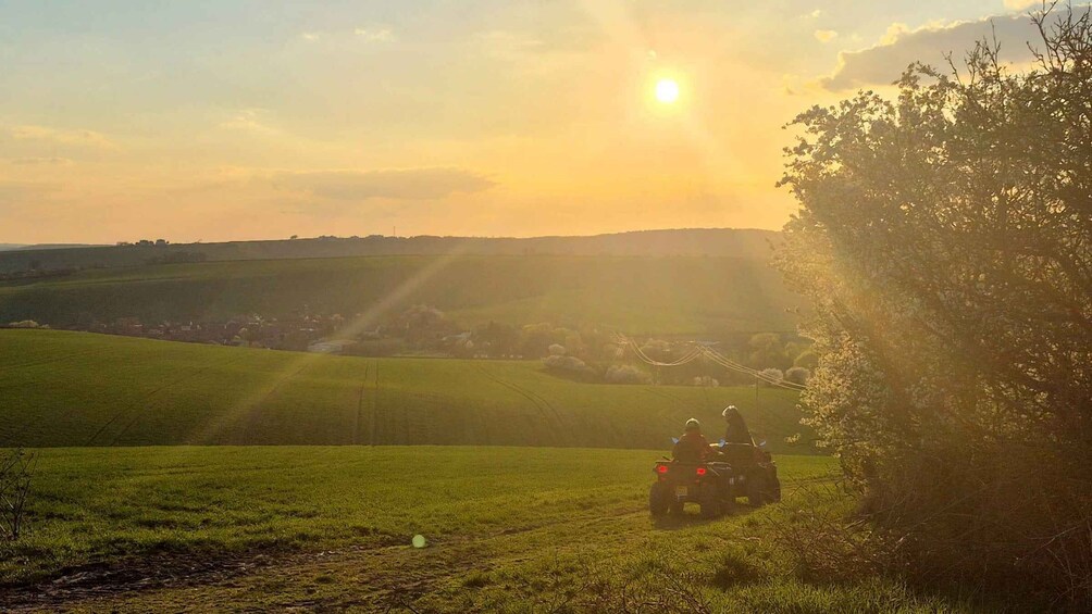 A quad bike on a grassy field with a sunset in the background. 3