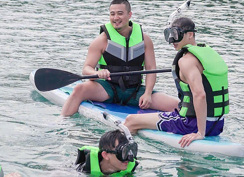 Three people on a paddleboard in the water, wearing life jackets. 4
