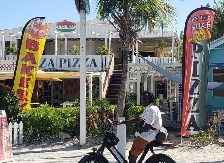 A person on a bicycle in front of a building with a sign that reads 'PIZZA PIZZA.' 2