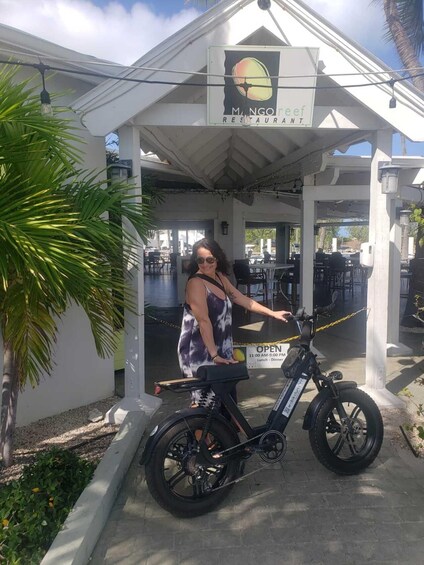 A woman on a bicycle in front of a restaurant named 'Mangrove Restaurant.' 4