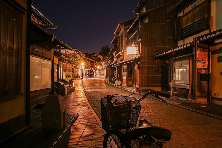 A nighttime street with traditional wooden buildings, a bicycle, and a clear sky. 1