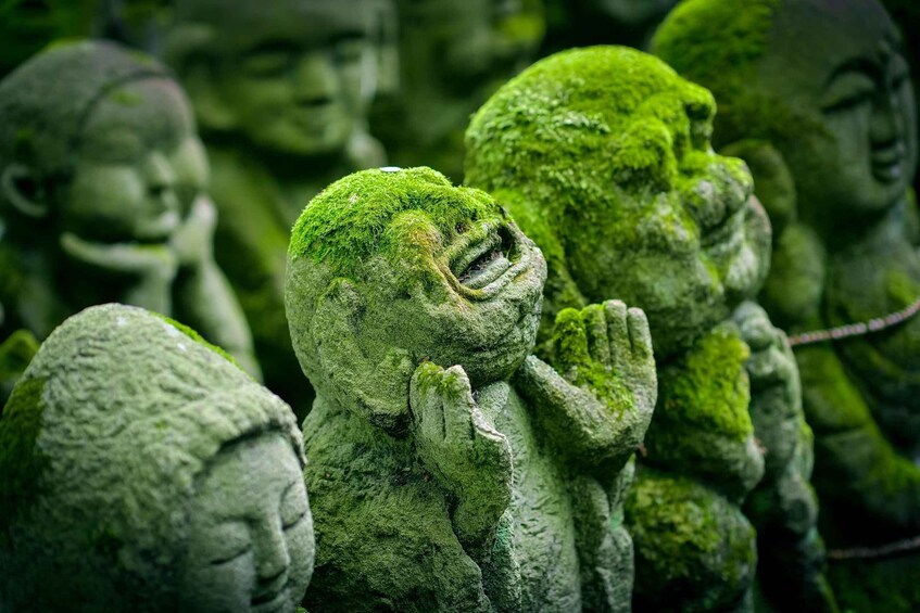 A collection of moss-covered statues in various poses. 2