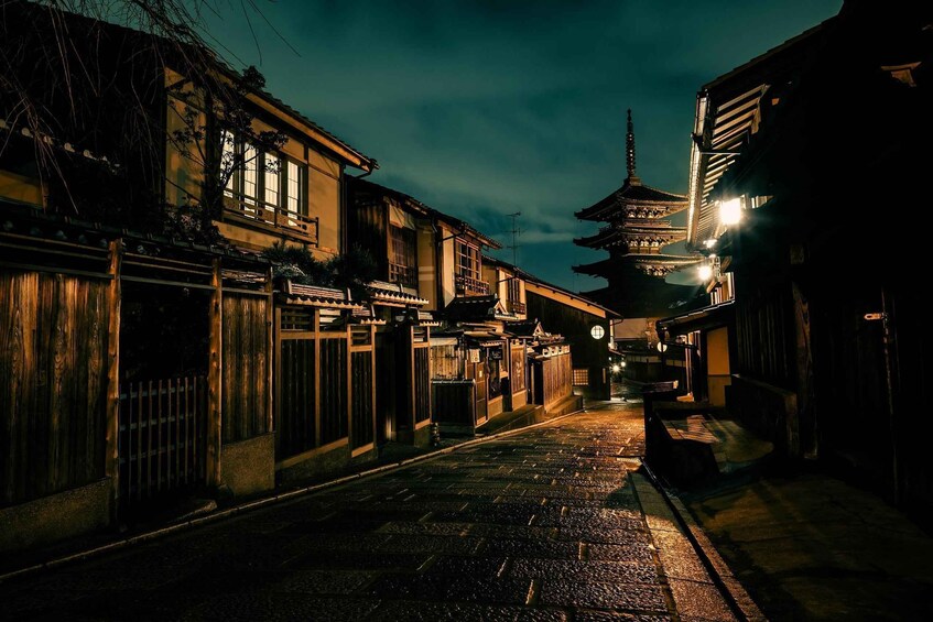 A traditional street at night with wooden buildings and a pagoda in the distance. 3