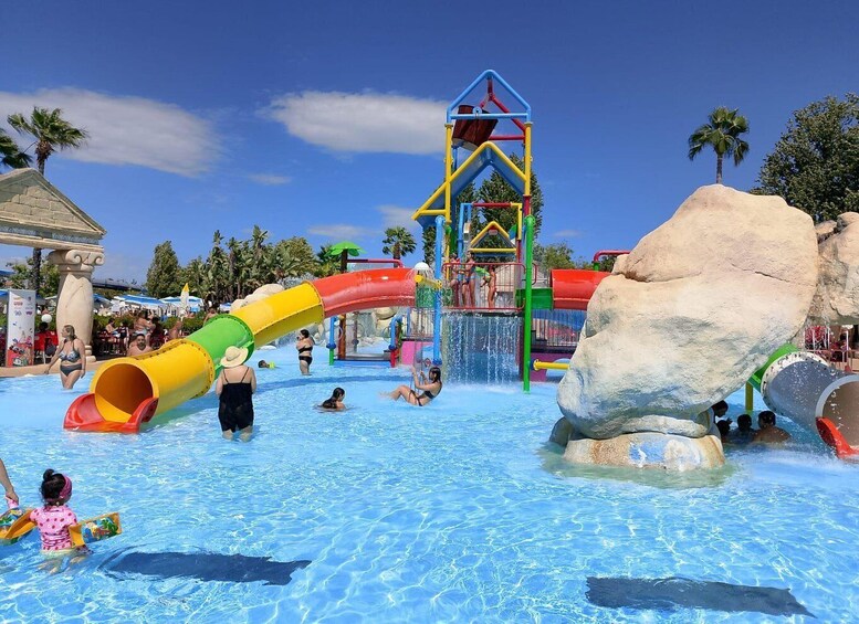 A water park with slides, a large rock formation, and a clear blue sky. 1