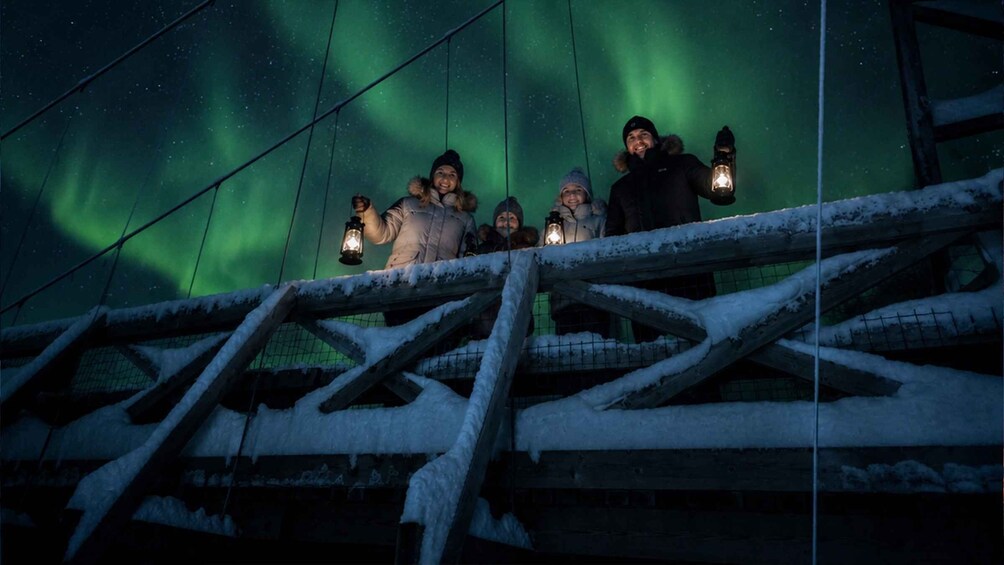 A group of people on a snowy platform with a view of the aurora borealis. 3