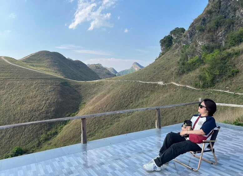 A person sitting on a chair overlooking a mountainous landscape with a clear sky. 5