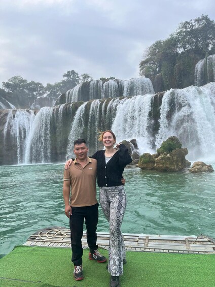 Two people standing on a dock with a waterfall in the background. 5