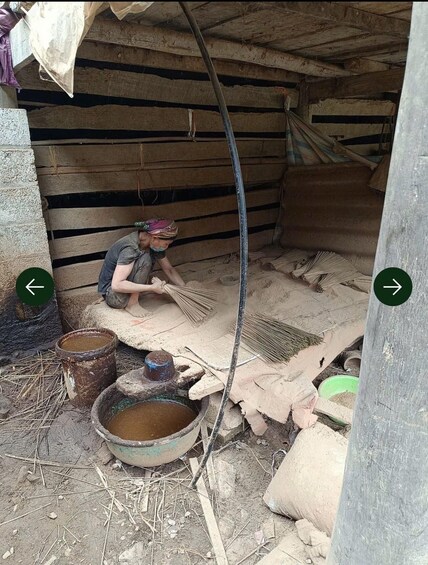 A person sweeping a wooden floor in a rustic setting with buckets and a hose. 1