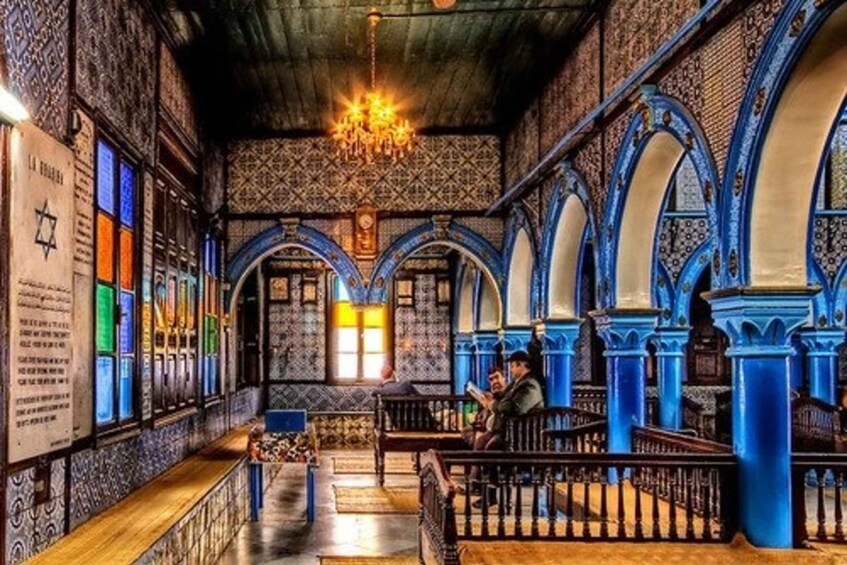 An interior with blue arches, a chandelier, and benches. 3