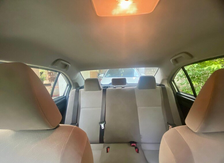 The interior of a car with beige seats, a central seatbelt, and a sunroof. 4