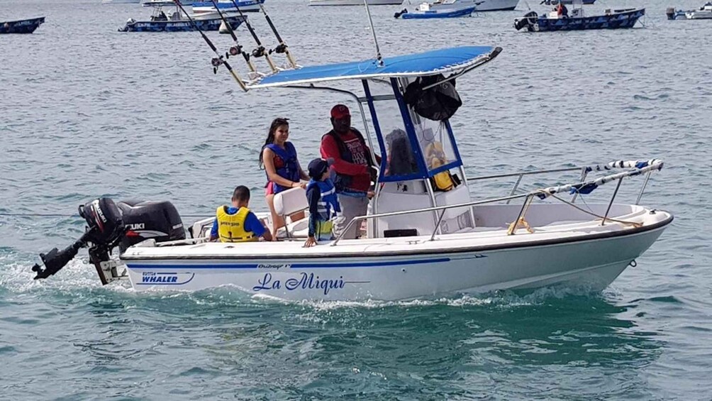 A boat named 'La Migui' with people on board, including a child and a woman in a blue swimsuit. 3