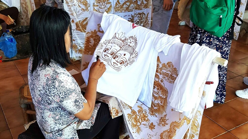 A person drawing on a white t-shirt with a floral pattern. 2