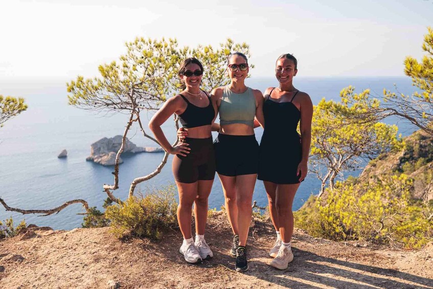 Three people standing on a cliff with a view of the sea and rocky coastline. 3