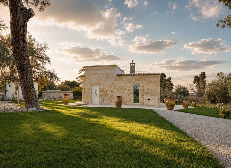 A stone building with a tiled roof, surrounded by a well-maintained lawn and large vases. 5