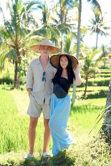 Two people standing in a field with palm trees in the background. 4