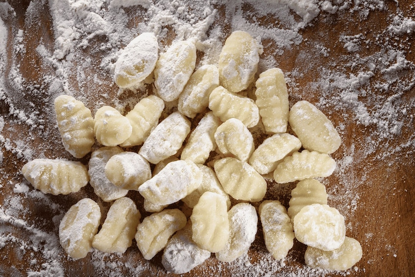 A pile of powdered doughnut holes on a wooden surface. 2