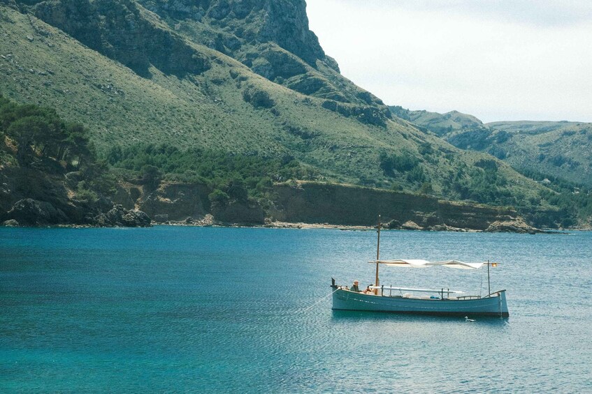 A boat on calm blue waters with a mountainous coastline in the background. 5