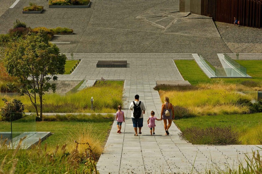 A family walking on a paved pathway surrounded by grass and plants. 4