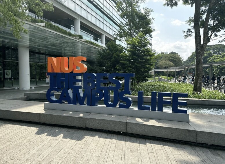 A campus sign with 'NUS' in orange and 'THE BEST CAMPUS LIFE' in blue. 5