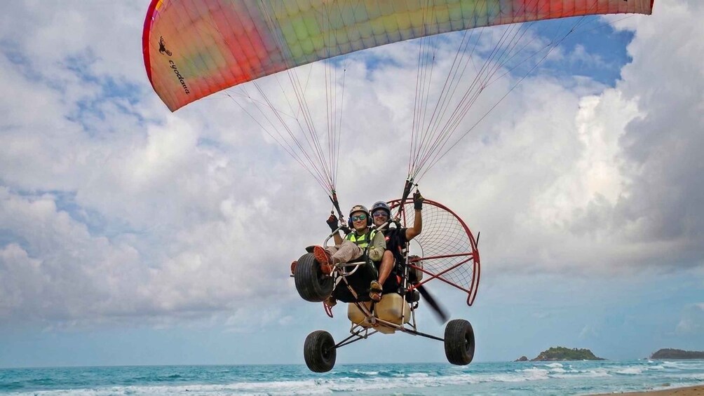 A tandem paragliding flight over the ocean with a colorful canopy. 1