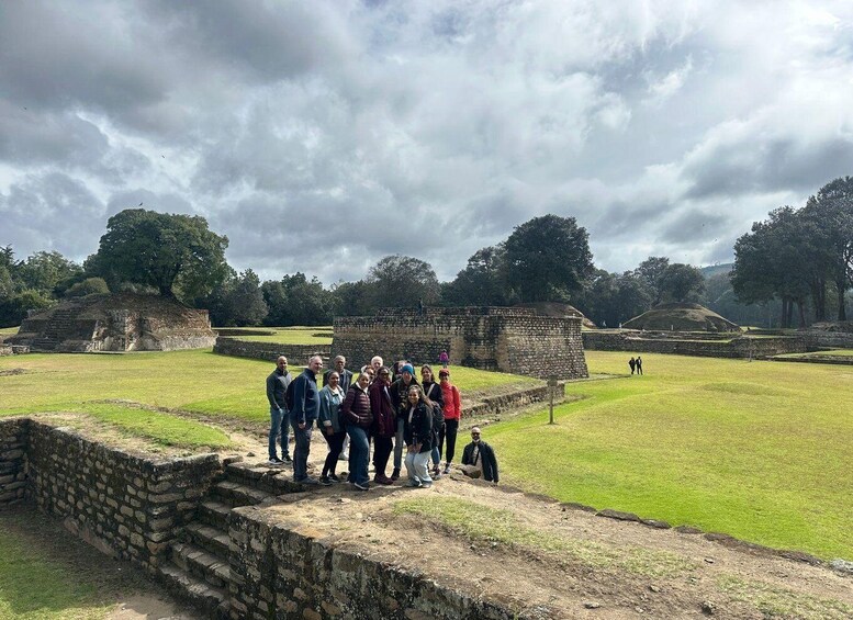 A group of people standing on a stone platform at an archaeological site with ancient ruins in the background. 5