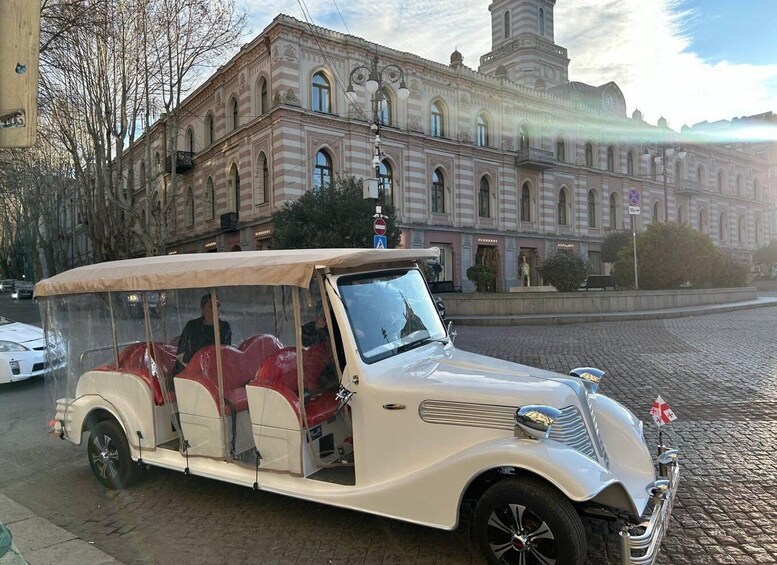 A vintage car parked on a cobblestone street in front of a historic building. 1