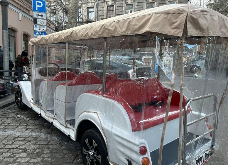 A vintage car with a transparent canopy, parked on a cobblestone street. 3