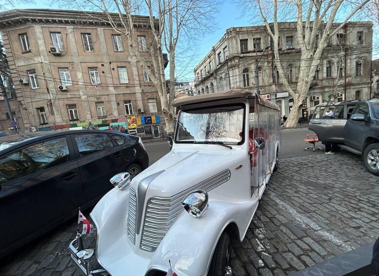 A vintage car parked on a cobblestone street with historic buildings in the background. 4