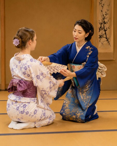 Two people in traditional Japanese kimonos performing a tea ceremony. 3