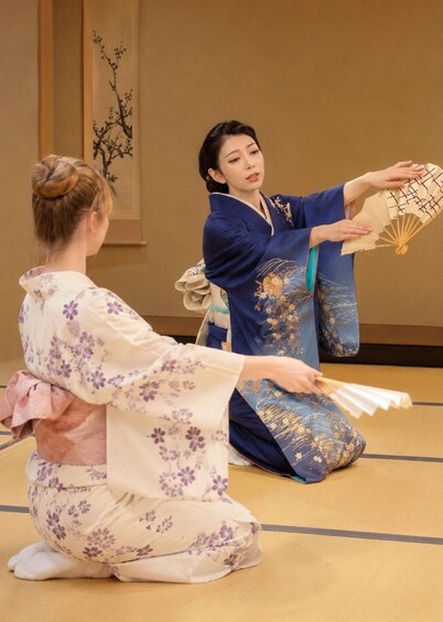 Two individuals in traditional Japanese kimonos performing a fan dance. 2