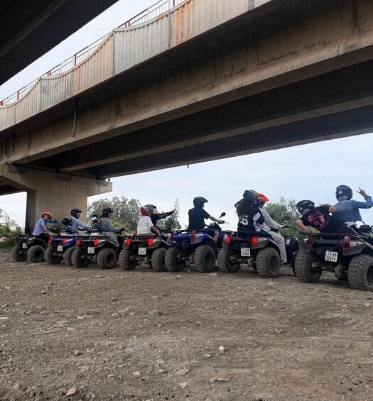 A line of quad bikes parked under a bridge. 5